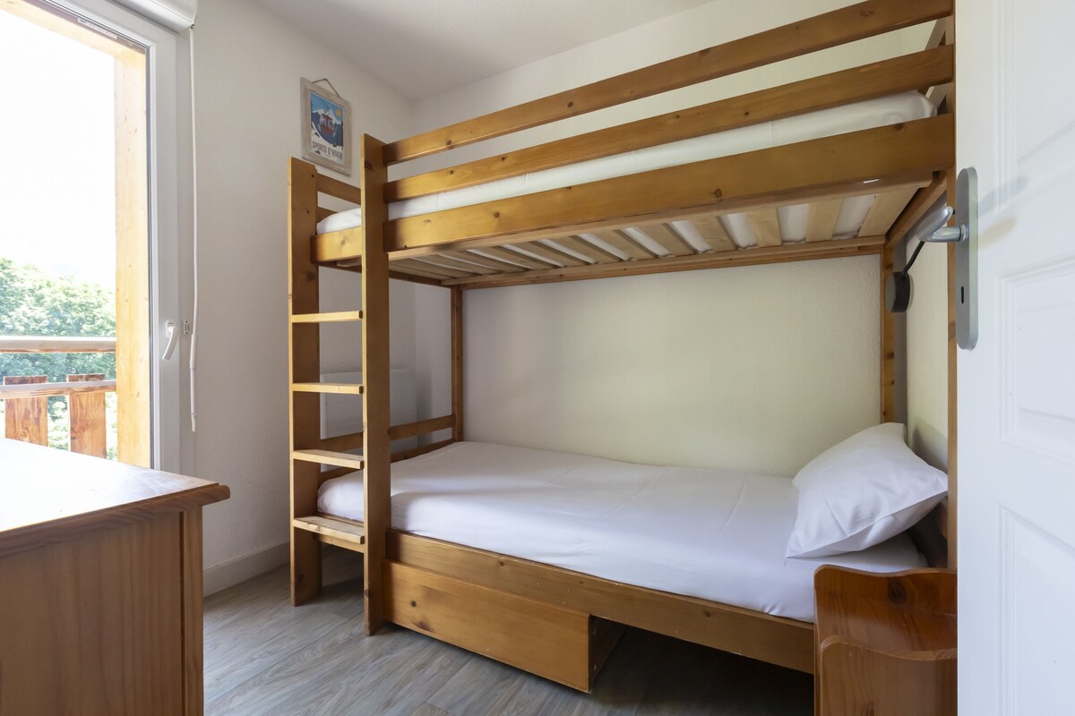 Una cama individual superpuesta con estructura de madera, un escritorio y una ventana.