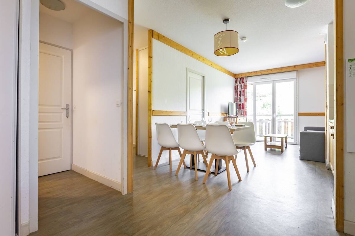 Ein Essbereich mit Holzbalkendecke, einem Tisch mit Stühlen und einem Fenster mit Vorhängen.