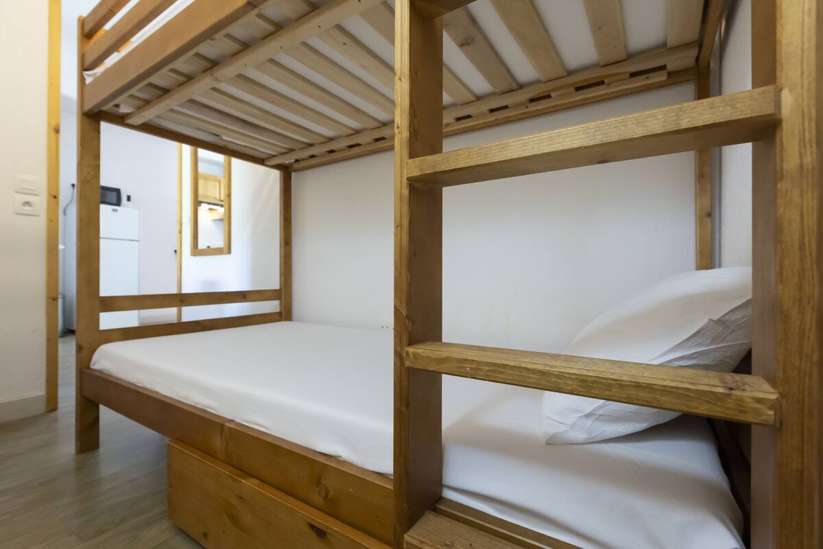 Ein Stockbett mit Holzrahmen und weißer Bettwäsche.