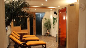 Un área de spa con tumbonas de madera, una sauna y un reloj en la pared.