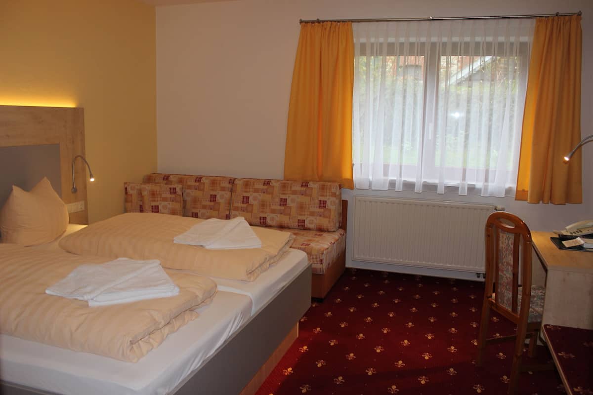 Una habitación de hotel con una cama, un escritorio y una silla.