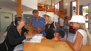 A group of people seated at a wooden table in a room with a staircase and a door in the background. - Résidence Odalys L'Orée des Pistes (Le Dévoluy)