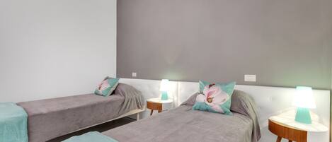 A hotel room with two single beds, each with a nightstand and a lamp.