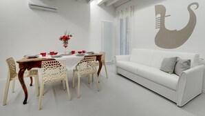 Una sala moderna con un sofá blanco, una mesa de comedor con sillas y una pared con diseño decorativo.