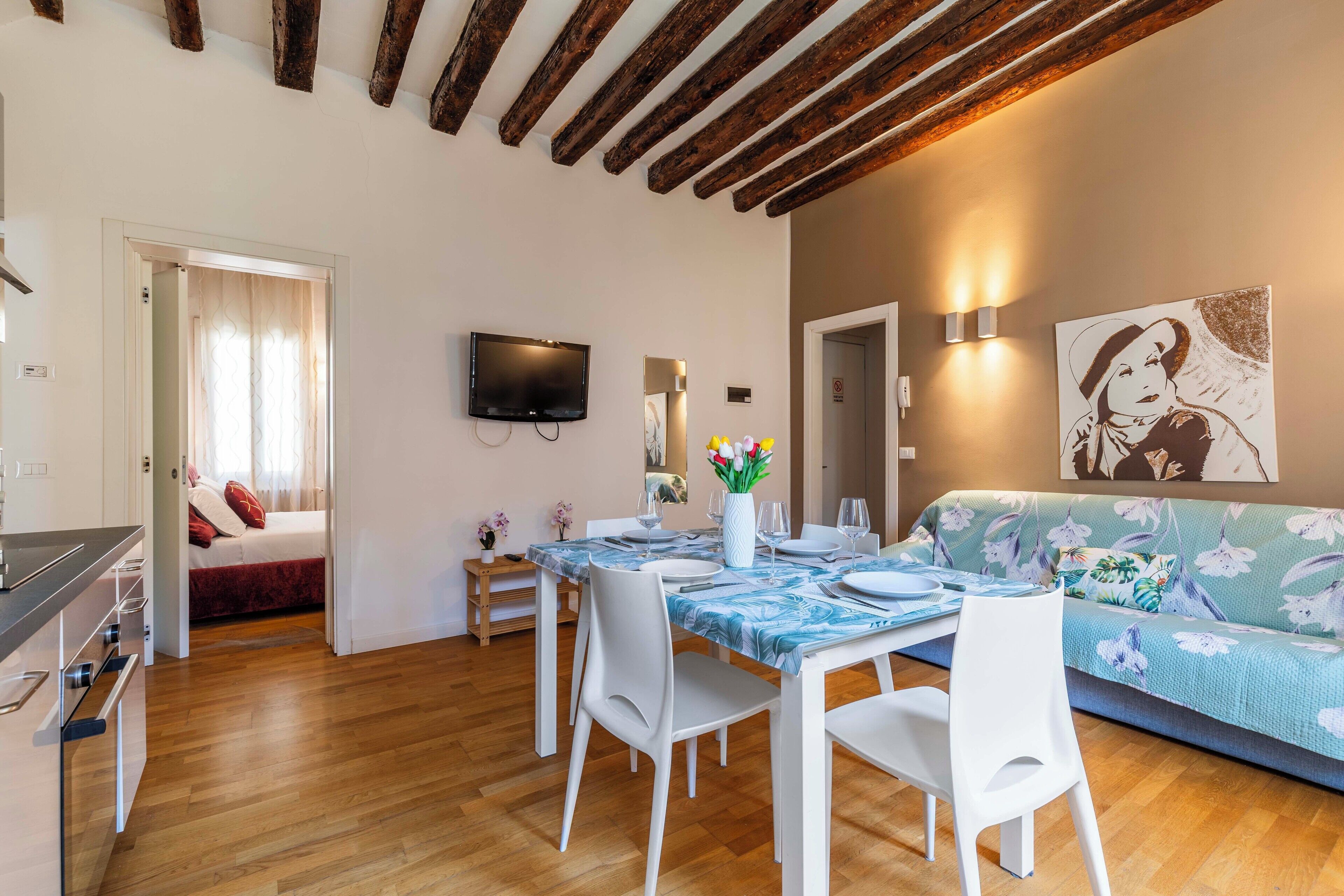 Un espacio habitable moderno con comedor, sofá y televisor de pantalla plana en la pared.