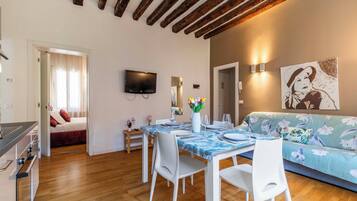 Un espacio habitable moderno con comedor, sofá y televisor de pantalla plana en la pared.