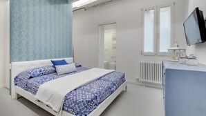 Un dormitorio con cama, cómoda, televisor y ventana.