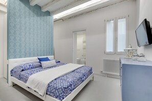 A bedroom with a bed, a dresser, a TV, and a window. - Bacchus Venice Residence by Wonderful Italy (Venice)