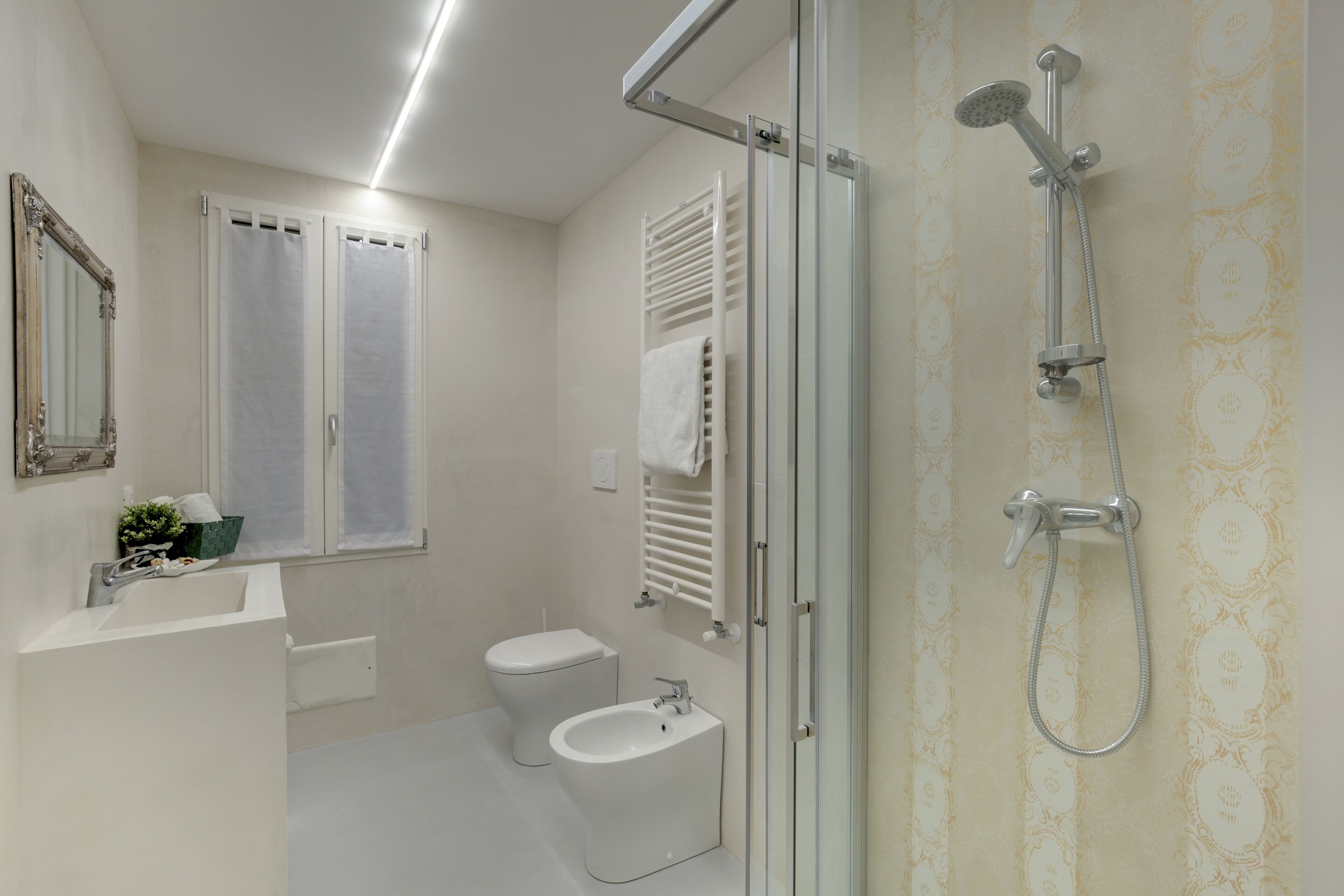 A modern bathroom with a shower, toilet, bidet, and sink.