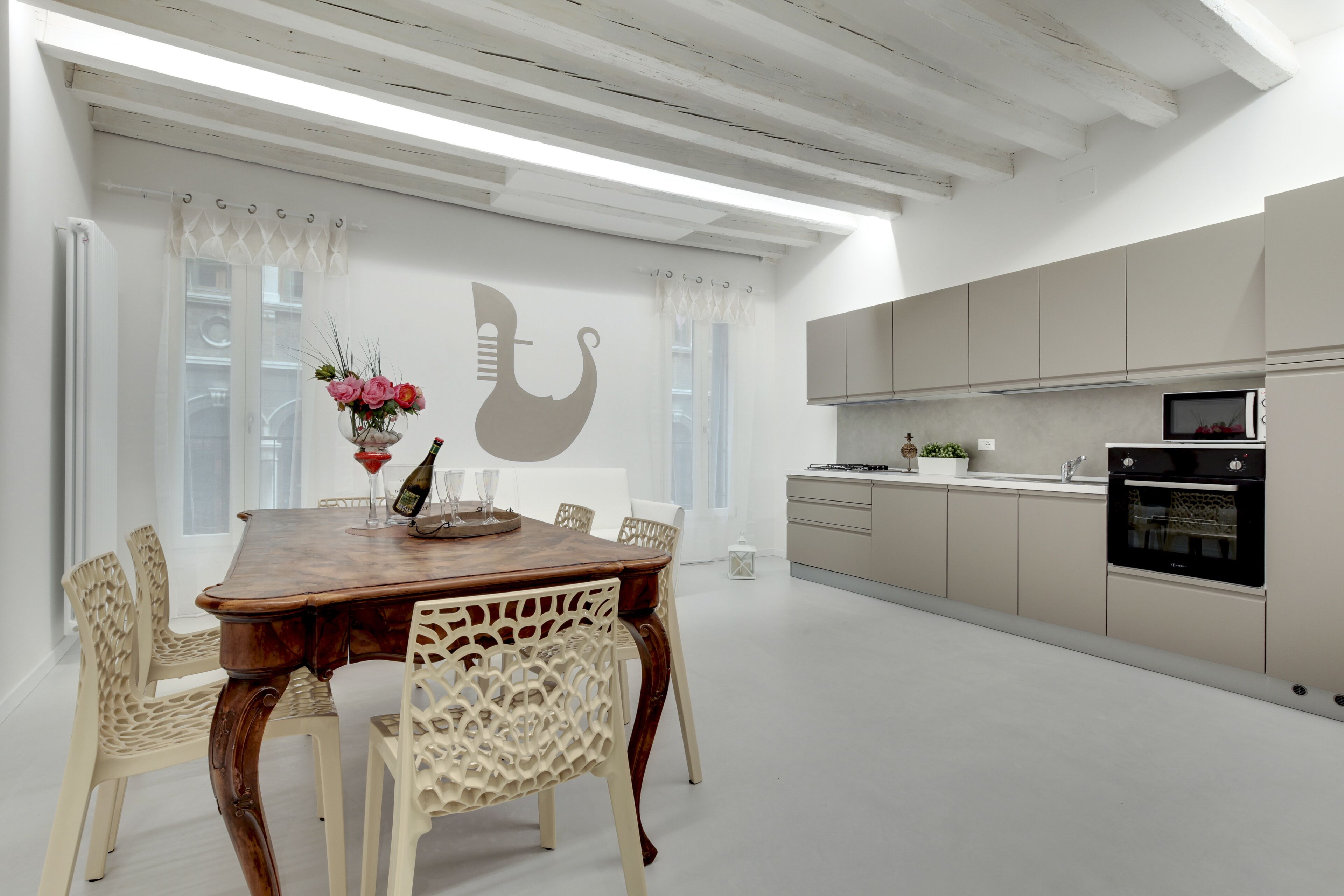 Un coin repas avec une table et des chaises en bois, un mur décoratif et une cuisine équipée d’armoires et d’appareils électroménagers.