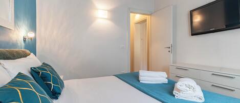 A hotel room with a bed, a TV, and a door leading to another room.