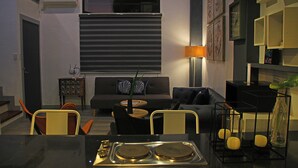 A modern living room with a sofa, armchairs, a coffee table, and a dining area with a table and chairs. - Bayview Country Inn El Nido (El Nido)