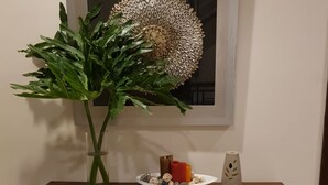 A wooden table with a vase of green foliage, a decorative plate with various items, and a wall-mounted artwork. - Bayview Country Inn El Nido (El Nido)