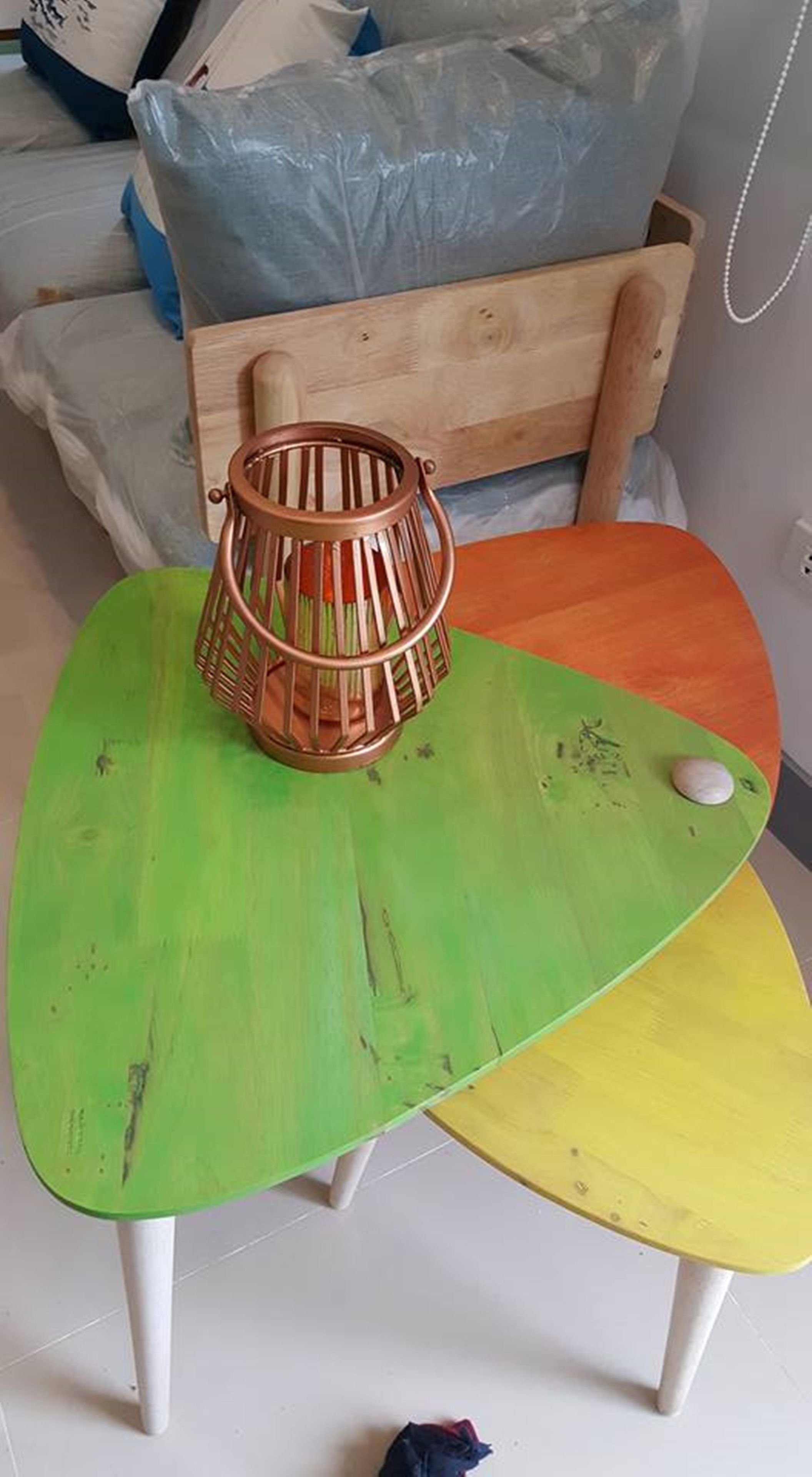 Una habitación con una mesa verde y amarilla, una silla de madera y una lámpara de metal.