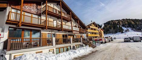 A hotel with wooden balconies, a sign reading "Hotel Grissly," and a snow-covered ground.