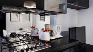Une cuisine moderne équipée d’une cuisinière à gaz, d’un grille-pain, d’une bouilloire et d’un téléviseur à écran plat.