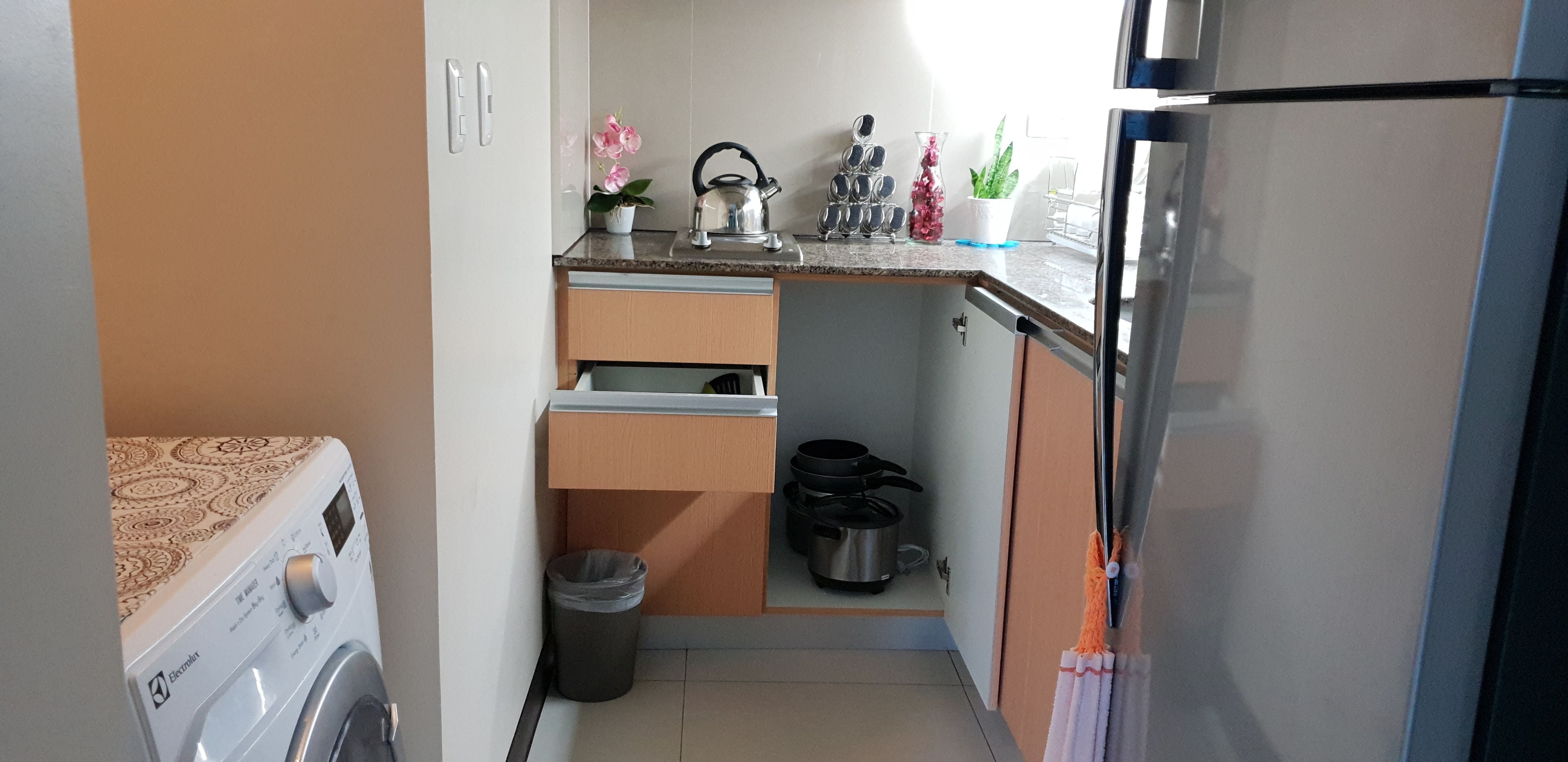 Une cuisine compacte équipée d’un lave-linge, d’un évier, d’une cuisinière et d’un réfrigérateur.