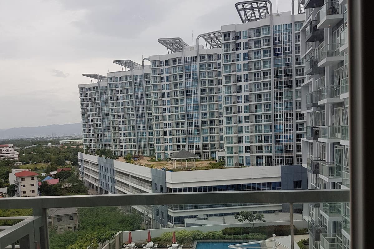 Un edificio residencial alto con varios balcones y un jardín en la azotea.