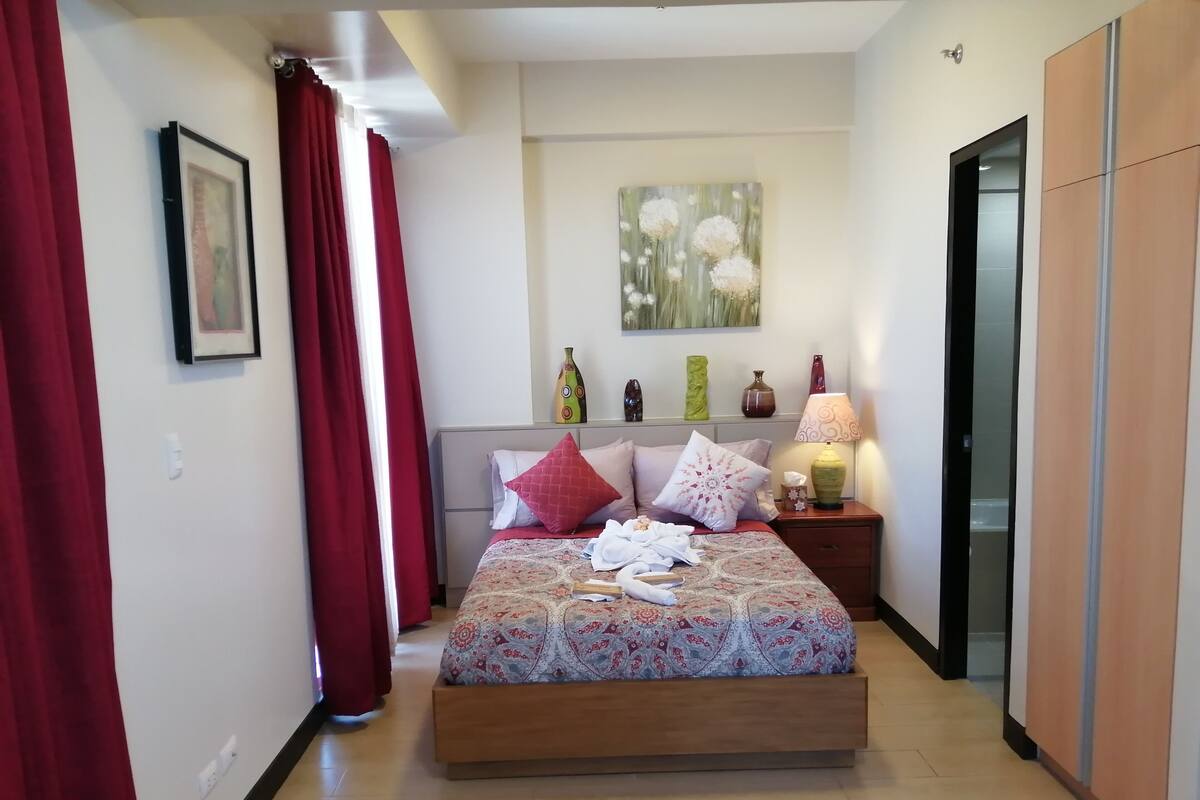 Un dormitorio con una cama, una mesita de noche, una lámpara y un cuadro en la pared.