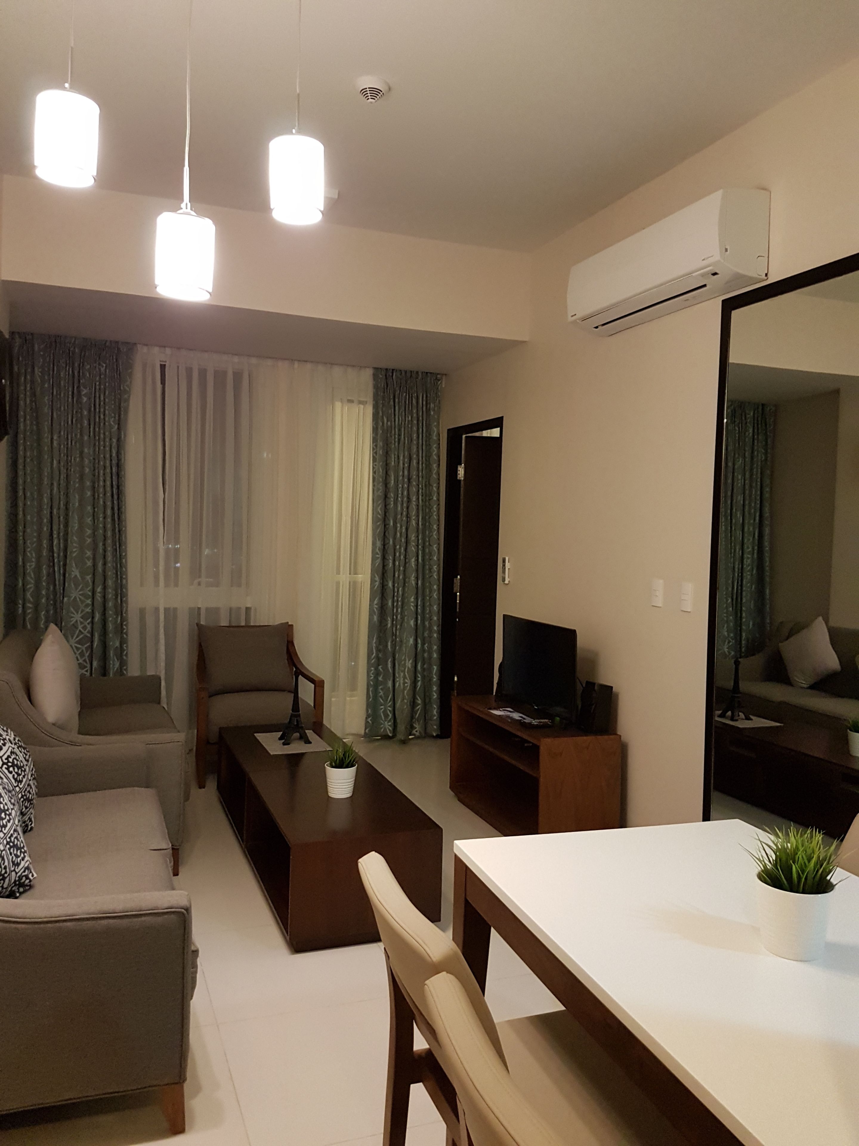 A modern living room with a sofa, a coffee table, a TV, and a dining area.