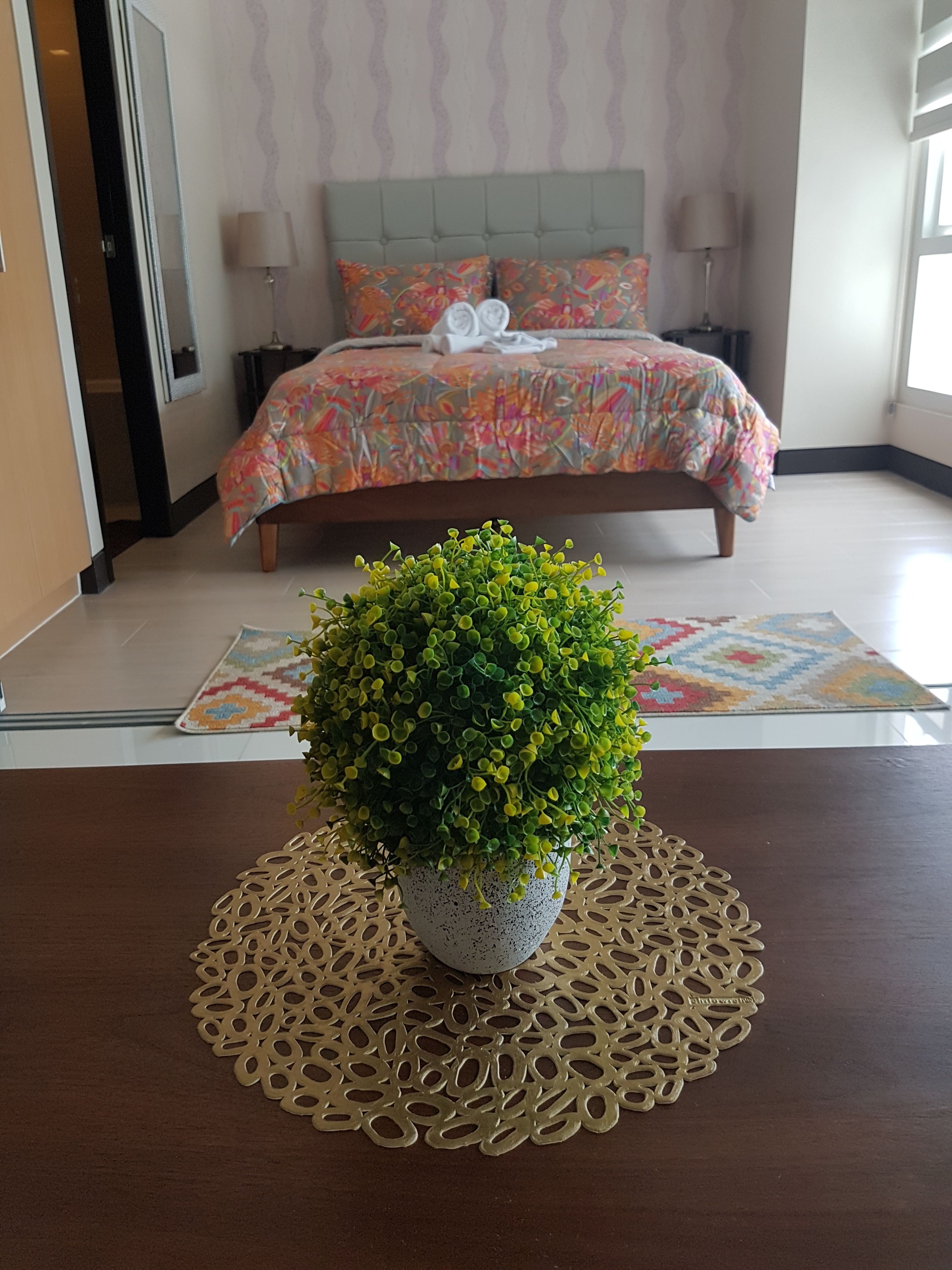 Une chambre à coucher avec un lit, une plante en pot et un tapis à motifs.