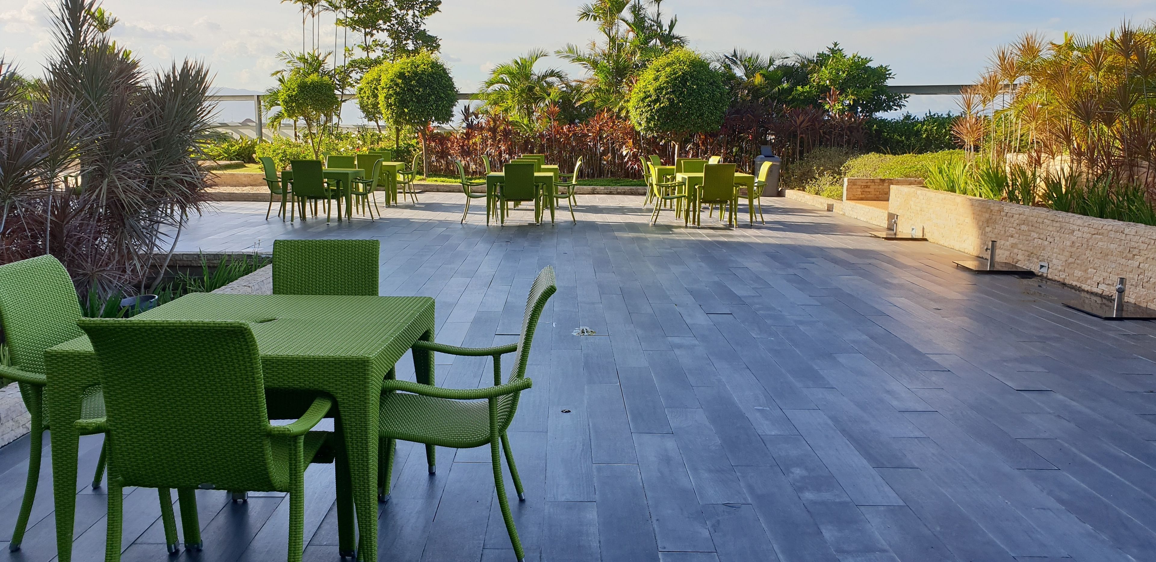 Un patio al aire libre con mobiliario de mimbre verde y vista al mar.