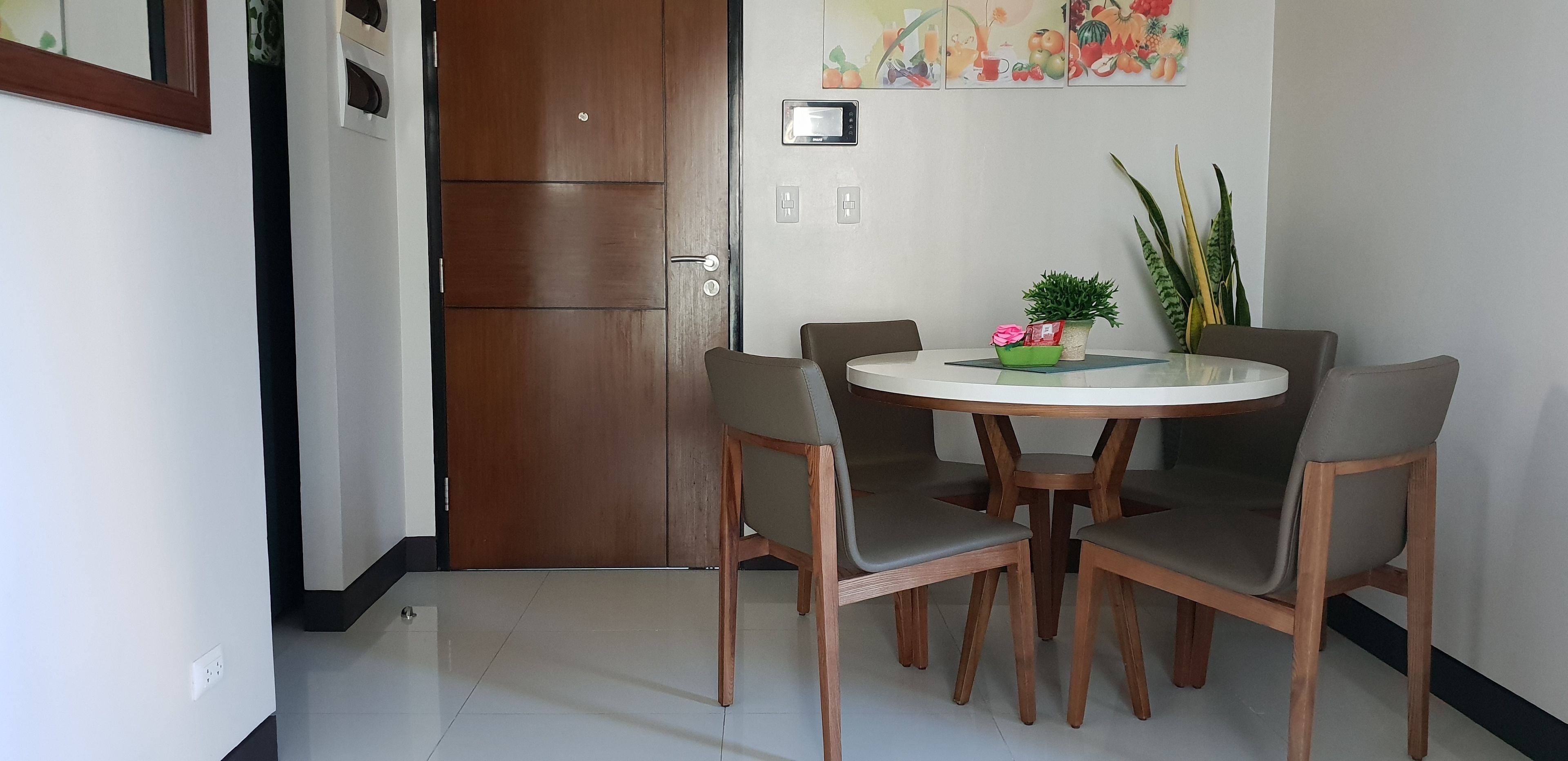 Un comedor con una mesa redonda, cuatro sillas y una planta en maceta sobre la mesa.