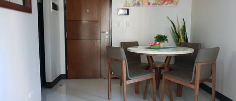 Un comedor con una mesa redonda, cuatro sillas y una planta en maceta sobre la mesa.