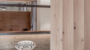 A modern hotel lobby with wooden paneling, a reception desk, and a visible logo. - Hotel Mathiesn (Soelden)