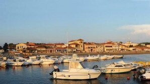 A marina with multiple boats docked, a coastal town in the background, and a clear sky. - Affittacamere Casa Brajan (Follonica)