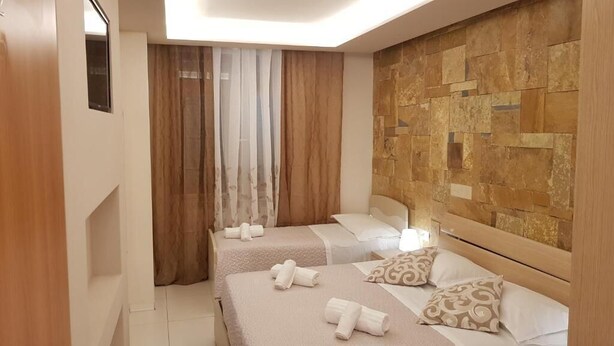 A hotel room with two beds, a stone wall, and a wooden headboard. - Affittacamere Casa Brajan (Follonica)