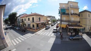 A street view with buildings, a crosswalk, and parked cars. - Affittacamere Casa Brajan (Follonica)