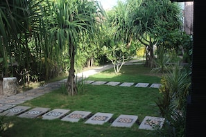 Un sentiero in giardino con piastrelle decorate, immerso nel verde e alberi.