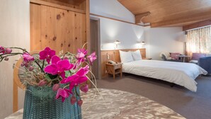 Une chambre à coucher avec un lit, des tables de chevet, une lampe et un vase rempli de fleurs.