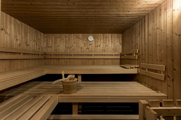 A sauna with wooden benches and a wooden bucket.