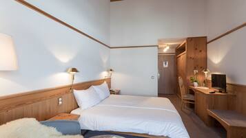 Une chambre à coucher comprenant un lit, des lampes de chevet, un bureau, une chaise et une armoire.