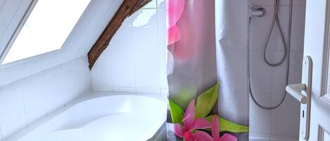 A bathroom with a skylight, a bathtub, a shower, and a floral shower curtain.