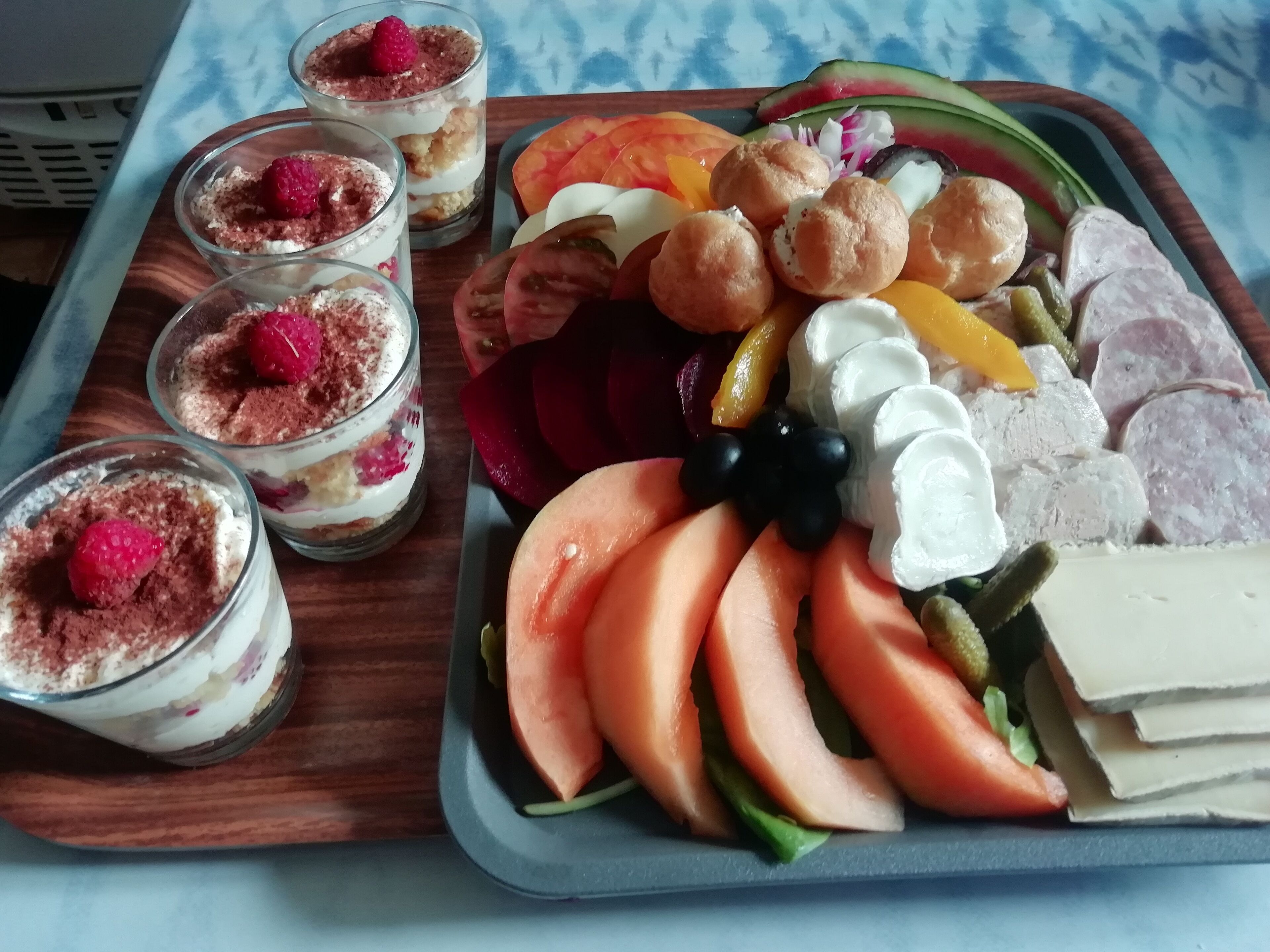 Un plateau contenant divers aliments, notamment des fruits coupés, du fromage et de petits desserts.