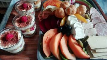 Un plateau contenant divers aliments, notamment des fruits coupés, du fromage et de petits desserts.