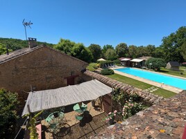 Um edifício de pedra com piscina, área de estar externa e jardim.