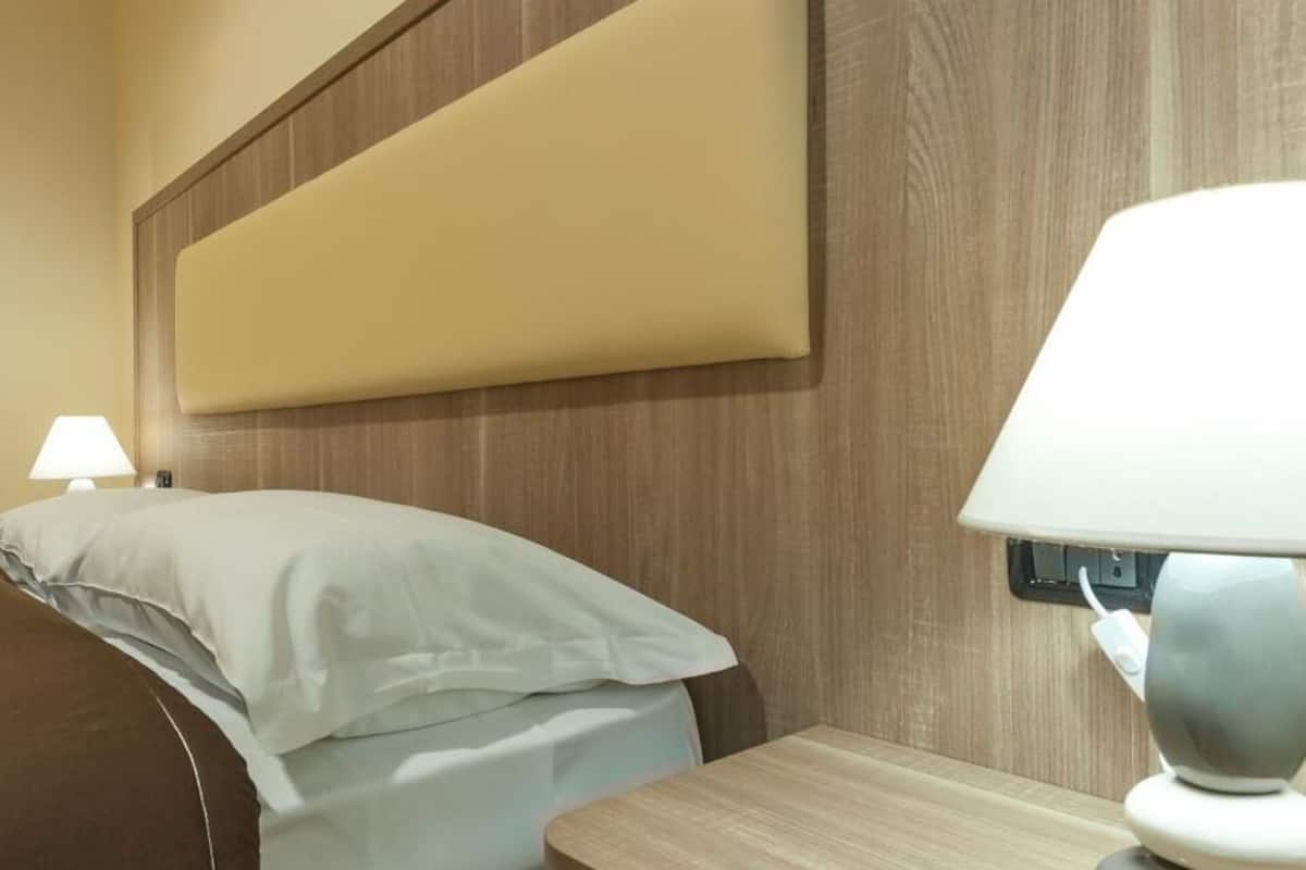 Una habitación de hotel con una cama, una mesita de noche y una lámpara.