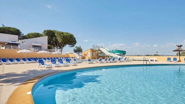 A swimming pool with lounge chairs and a water slide. - Domaine Résidentiel de Plein Air Odalys La Pinède (Agde)