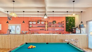 A pool table with balls, a bar area with shelves of bottles, and a green wall with plants. - Domaine Résidentiel de Plein Air Odalys La Pinède (Agde)