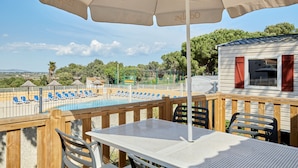 A poolside area with lounge chairs, a table, and an umbrella. - Domaine Résidentiel de Plein Air Odalys La Pinède (Agde)