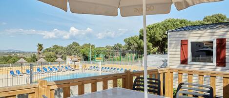 Un espace aménagé au bord de la piscine, avec des chaises longues, une table et un parasol.