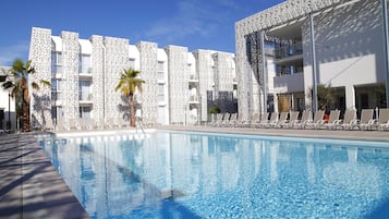 Una piscina al aire libre, sillones reclinables de piscina