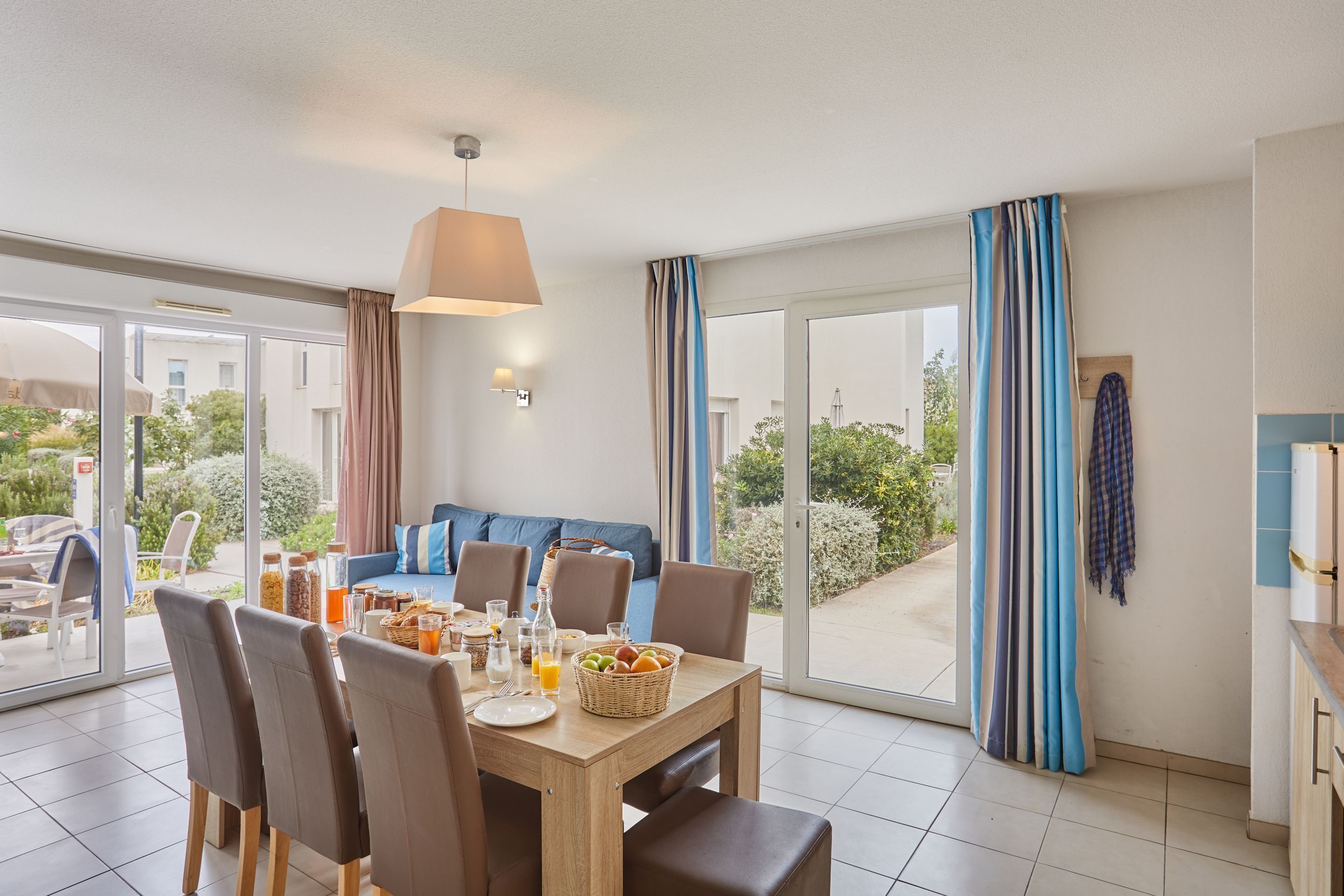 A dining area with a table set for breakfast, a sofa, and a view of the outdoors.