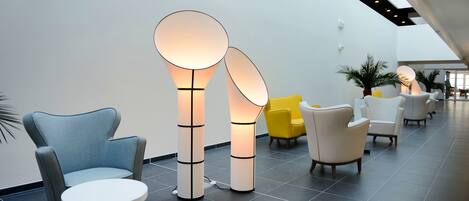 A modern lobby with contemporary seating, including a blue armchair and a white round table.