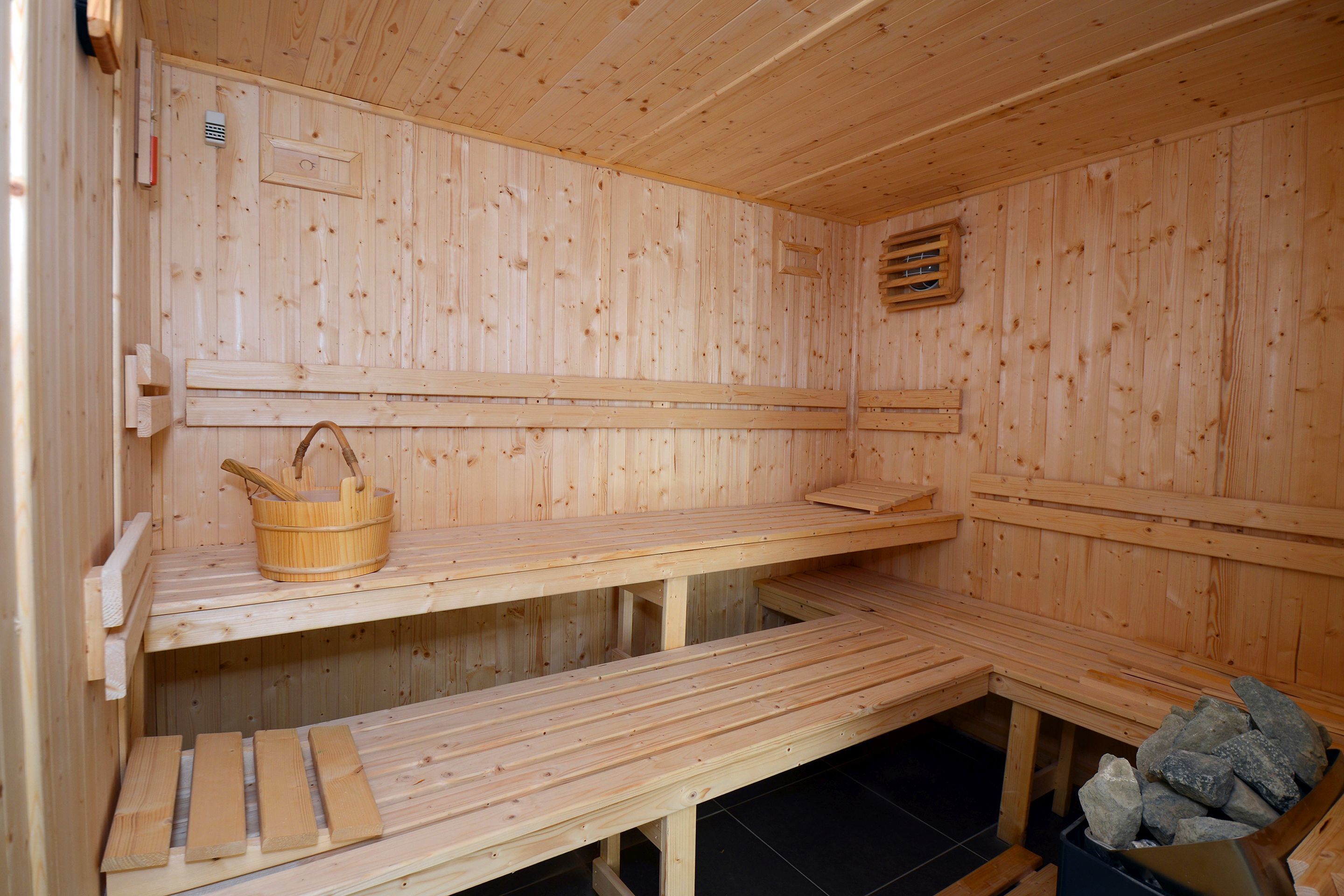 A wooden sauna with benches and a stone-filled container.