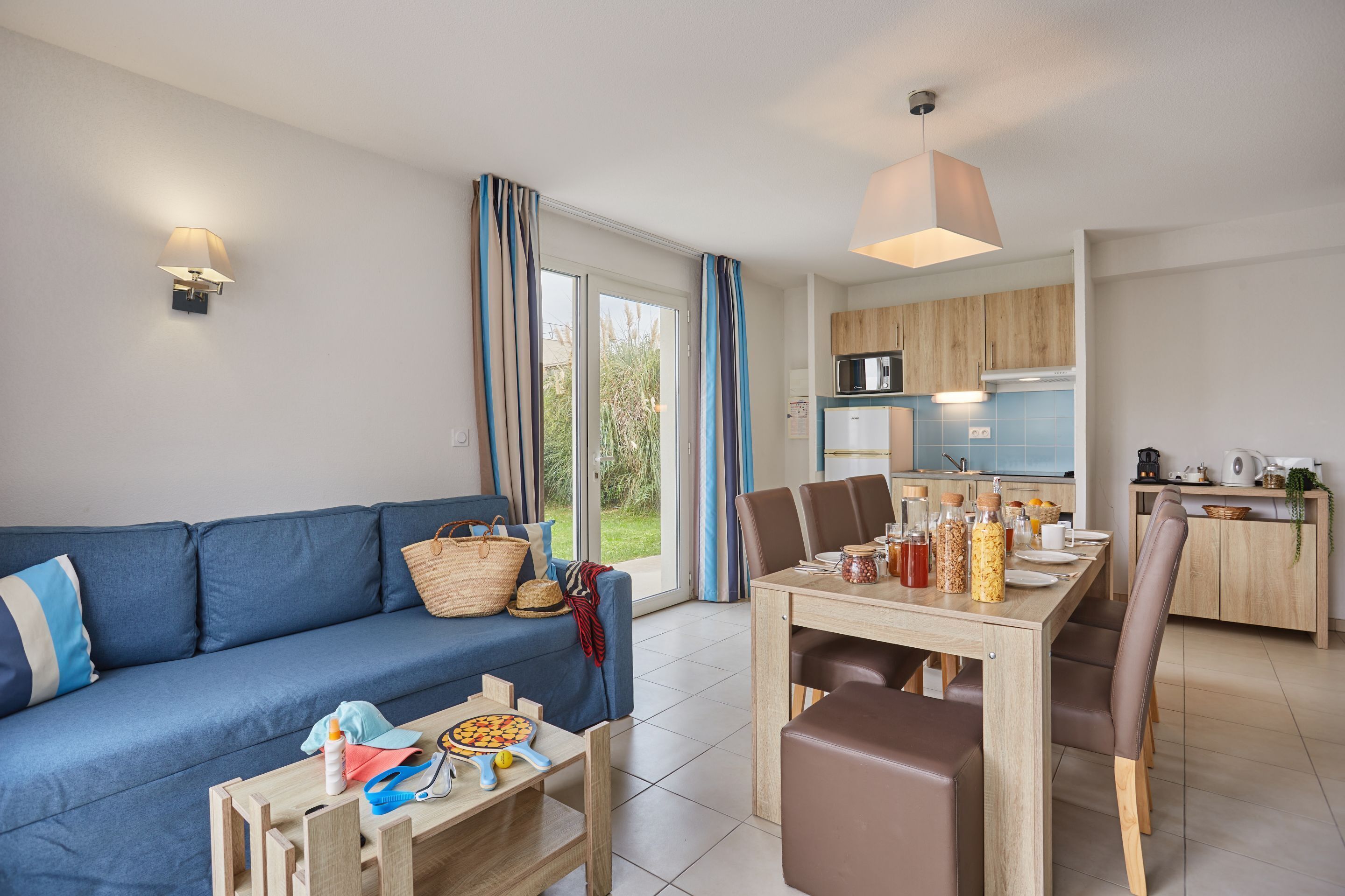 Ein modernes Wohnzimmer mit Sofa, Esstisch und Küchenzeile.